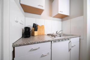 a small kitchen with white cabinets and a sink at Favorite Stays - Suite and More - Westfeld in Neuss
