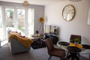 a living room with a table and a clock on the wall at Cosy 2-Bed House in Nottingham in Nottingham