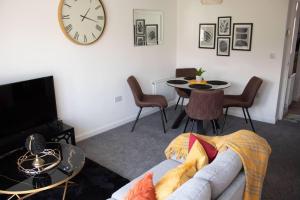 a living room with a couch and a clock on the wall at Cosy 2-Bed House in Nottingham in Nottingham