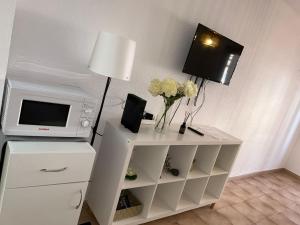 biała szafka z telewizorem i wazonem kwiatów w obiekcie Castle 411 w mieście Los Cristianos