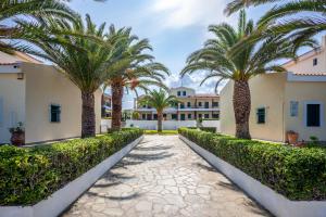 a pathway with palm trees in front of a building at Seaside Bungalow in Pefkochori