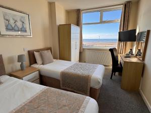 a hotel room with two beds and a desk and a window at Craig-y-Don in Blackpool