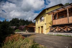 ein gelbes Haus mit einem Holzzaun neben einem Gebäude in der Unterkunft Ferienhaus Seetaler Alpen in Obdach