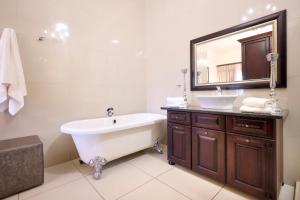 uma casa de banho com uma banheira, um lavatório e um espelho. em Postmasburg d Olive Rose Boutique Hotel em Postmasburg