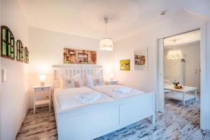 a white bedroom with a white bed and a mirror at Oma's Küche & Quartier in Binz
