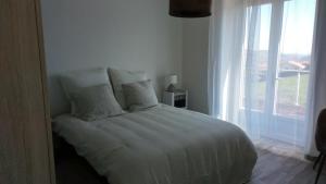 Cama blanca en habitación con ventana en Détour en Beaujolais en Les Ardillats