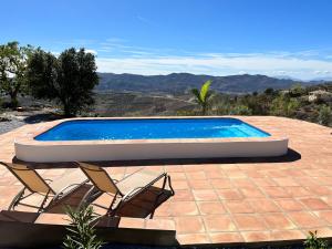a swimming pool with two chairs sitting next to it at Casa Pura Vida - Malaga - Andalusië in Colmenar