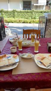 a table with plates of food and glasses of orange juice at Liberty Place in Luang Prabang