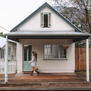a woman walking out of a white house at The Old Shop - Byron Region Hinterland 