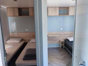 维亚斯superbe mobil home 6/8 pers,clim, sans vis a vis dans camping 4* espace aquatique的有两张床和一扇窗户的小房间