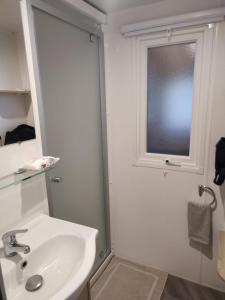 维亚斯superbe mobil home 6/8 pers,clim, sans vis a vis dans camping 4* espace aquatique的带水槽和窗户的白色浴室