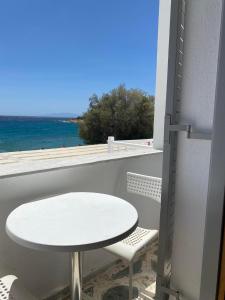 d'une table et d'une chaise blanches sur un balcon donnant sur l'océan. dans l'établissement Fisilanis Beachfront Hotel, à Logaras