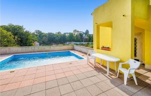 a patio with a white table and chairs next to a pool at Stunning Apartment In Marcana With 3 Bedrooms And Wifi in Loborika
