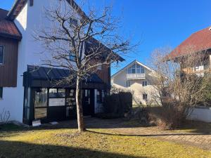 un árbol en un patio al lado de una casa en Gemütliches Loft en Geretsried