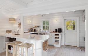 a white kitchen with a large white counter and stools at Nice Home In Nykbing Sj With Wifi in Tjørneholm