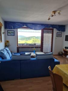 uma sala de estar com um sofá azul e uma janela em Ferienwohnung Sonnenblume mit Hallenbad und Sauna em Missen-Wilhams