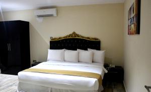 a bedroom with a bed with a black and gold headboard at Ellyxville Hotel in Lekki