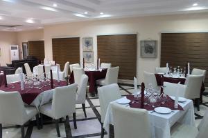 a dining room with tables and white chairs and tablesearcher at Ellyxville Hotel in Lekki