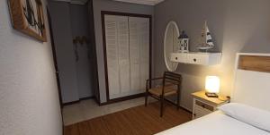 a bedroom with a bed and a chair and a mirror at Apartamento a 30 metros de la playa in San Vicente de la Barquera