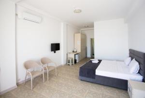 a hotel room with a bed and chairs and a tv at Domus Hotel in Aktau