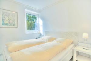 ein weißes Schlafzimmer mit 2 Betten und einem Fenster in der Unterkunft Windeby 3T in Wenningstedt-Braderup