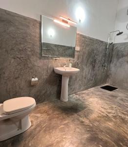 a bathroom with a sink and a toilet and a mirror at The Dom hotel & restaurant in Ahangama
