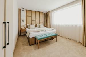 a bedroom with a bed and a bench and a window at SPA Hotel Green Park in Garmen