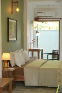 um quarto com uma cama, uma mesa e uma janela em Temple Tree em Weligama