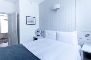 a white bedroom with a white bed and a lamp at Ground floor apartment at Number 8: king bed, en-suite, lounge, kitchenette in Kent