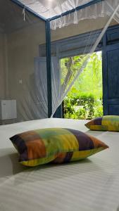 a colorful pillow on a bed with a window at Kataragama Homestay in Kataragama