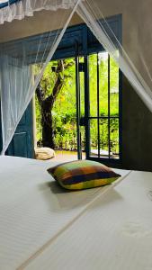 a bed with a pillow in front of a window at Kataragama Homestay in Kataragama