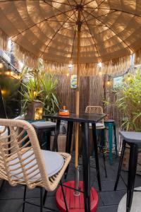 una mesa y sillas bajo una sombrilla en un patio en Les Fauvelles Paris La Défense en Courbevoie