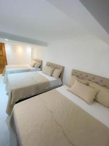 two beds in a room with white walls at Residence Pipa Beach in Pipa