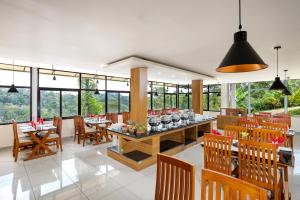 a dining room with tables and chairs and windows at Le Serene Munnar Resorts & Spa in Ūdumbanshola
