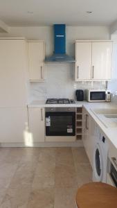 cocina con armarios blancos y fogones en Harington Homes en Palmers Green