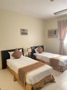Habitación de hotel con 2 camas y ventana en المواسم الاربعة للاجنحه الفندقية en Al Jubail