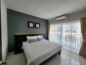 a bedroom with a bed and a large window at LHC HOTEL AND RESORT in Pattaya