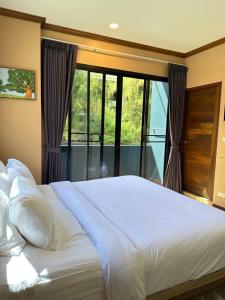 a bedroom with a large white bed and a window at Kata Noi Place in Kata Beach