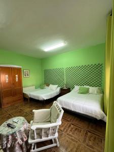 a green room with two beds and a table and chairs at Hostal Cabañeros in Ciudad Real
