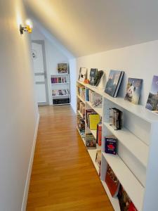 a hallway with white shelves filled with books at maison philirina in Athée-sur-Cher