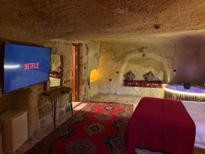 a bedroom with a bed and a flat screen tv at Kale House Nar in Nevsehir