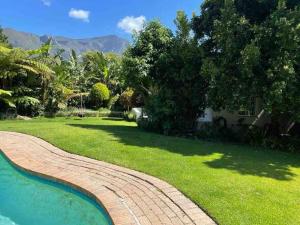 a brick walkway around a yard with a swimming pool at Charming 2 Bed en-suite Cottage with Solar in Cape Town