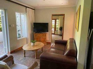 a living room with a couch and a television at Charming 2 Bed en-suite Cottage with Solar in Cape Town