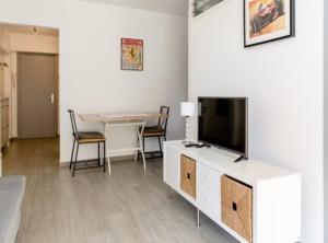 ein Wohnzimmer mit einem TV und einem Tisch mit Stühlen in der Unterkunft Apartamentos Playa Caballo Blanco in Salou