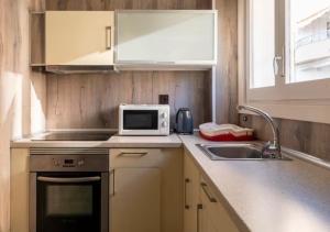 eine kleine Küche mit einer Spüle und einer Mikrowelle in der Unterkunft Apartamentos Playa Caballo Blanco in Salou