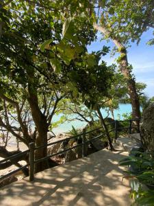 a wooden fence next to a beach with trees at Kata Noi Place in Kata Beach