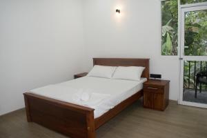 een slaapkamer met een bed met witte lakens en een raam bij SERENE HOME in Kandy