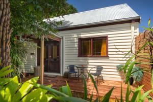 Casa blanca con sillas y una mesa en una terraza en Harem Cottage Gembrook - Spa Bath & Wood Fireplace en Gembrook