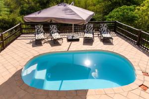 - une piscine bleue avec des chaises et un parasol dans l'établissement Amazing mountain views! Solar powered!, à Hoedspruit
