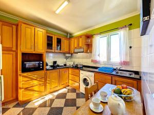a kitchen with wooden cabinets and a table with a bowl of fruit at Domus Dino in Porto da Cruz